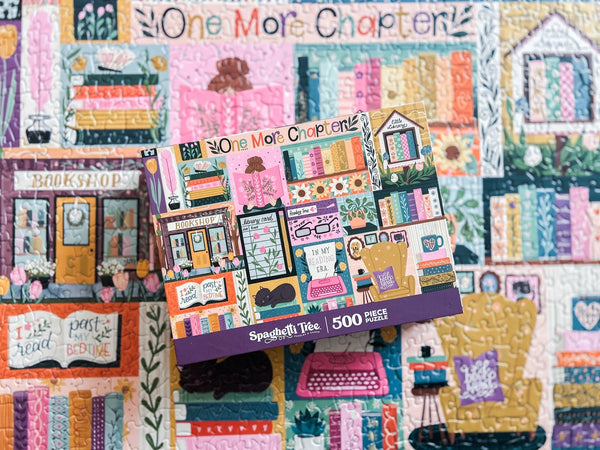 Puzzle box with 'One More Chapter' design above a blurred photo of the completed puzzle