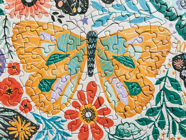 Close-up of completed puzzle section showing illustrated butterfly with yellow wings surrounded by florals and leaves.