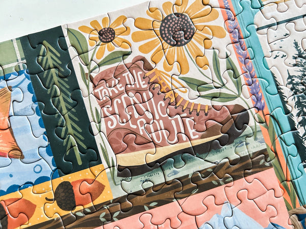 Jigsaw puzzle with scenic design featuring a boot and sunflowers. Text on boot reads Take the Scenic Route.
