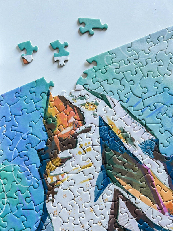 Jigsaw puzzle with a colorful design on a light blue background. Puzzle is nearly complete, but missing three pieces which sit nearby.