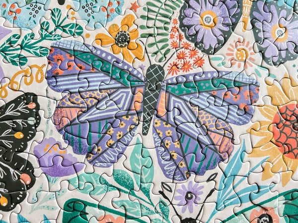 Colorful puzzle close-up with a illustrated butterfly design surrounded by flowers and leaves