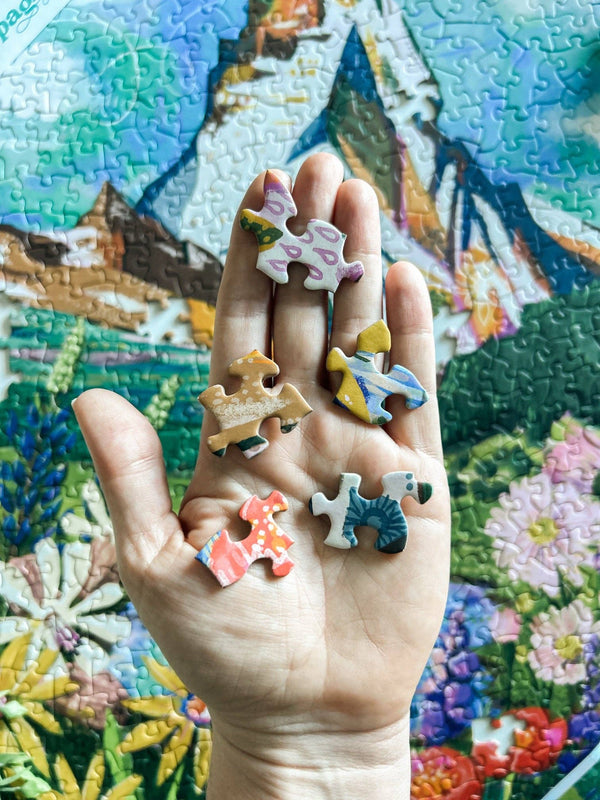 Hand holding colorful puzzle pieces with a partially completed puzzle in the background