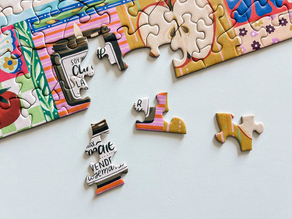 Close up of colorful puzzle section with some pieces nearby on a light gray background