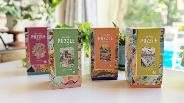 4 bright Lantern Press Firelight Collection puzzle boxes sitting on desk in front of plants.