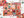 A colorful autumn-themed jigsaw puzzle with pieces scattered around it on a white surface, alongside the puzzle box and partial matching puzzle pieces. The puzzle features a patchwork design of pumpkins, leaves, plaid patterns, and fall motifs in orange, pink, teal, brown, and cream tones.