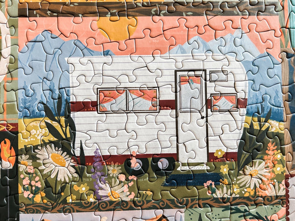 Close up of a completed puzzle section with a camper scene in a nature setting