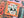 A close-up of a completed jigsaw puzzle featuring a skull with roses growing out the eye holes on an orange background, surrounded by Halloween-themed illustrations including a jack-o'-lantern and candy corn.
