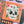 A close-up of a completed jigsaw puzzle featuring a skull with roses growing out the eye holes on an orange background, surrounded by Halloween-themed illustrations including a jack-o'-lantern and candy corn.