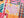 A close-up of a completed jigsaw puzzle featuring a colorful autumn design with the words 'Hello fall' in pink script, orange pumpkins, teal leaves, and plaid patterned sections.