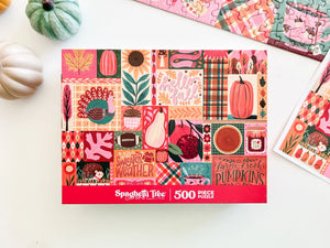 A 500-piece jigsaw puzzle box by Spaghetti Tree, featuring a colorful autumn patchwork design with pumpkins, leaves, and fall phrases, styled on a white surface with decorative pumpkins and partial puzzle pieces.