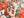 A hand holding several small, colorful Christmas-themed puzzle pieces, over top the completed puzzle shown out of focus.