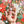 A hand holding several small, colorful Christmas-themed puzzle pieces, over top the completed puzzle shown out of focus.