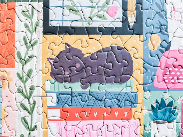 Close-up of a section of a jigsaw puzzle  showing art of a cat sleeping on books 