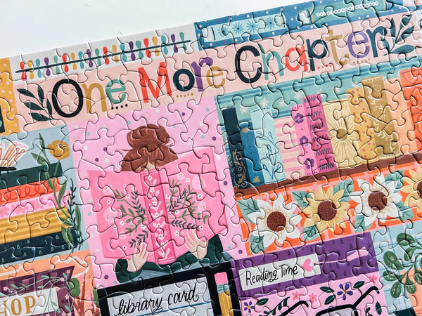 Close up of a portion of a colorful puzzle with 'One More Chapter' text and book-themed design.