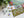 A Christmas-themed jigsaw puzzle set on a white surface, with several pieces scattered nearby and evergreen branches in the top left corner. The puzzle features holiday illustrations and the words 'HO HO HO' in large white letters with red and green accents.