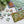A Christmas-themed jigsaw puzzle set on a white surface, with several pieces scattered nearby and evergreen branches in the top left corner. The puzzle features holiday illustrations and the words 'HO HO HO' in large white letters with red and green accents.