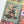 A close-up of a completed jigsaw puzzle showing a Halloween-themed design with a witch's hat, yellow flowers, spiderwebs, bats, and a jack-o'-lantern and a multicolored background on a white surface.