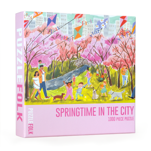 Puzzle box titled 'Springtime in the City' by PuzzleFolk with colorful illustration of people in a park full of trees with pink leaves. 