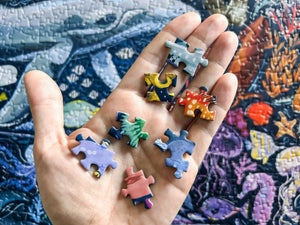 Colorful puzzle pieces held in a hand with a partially completed puzzle in the background.