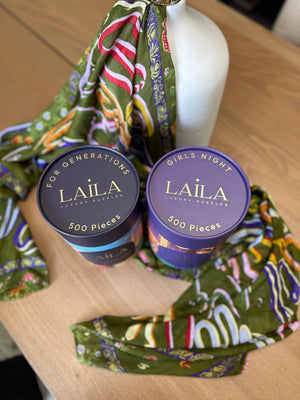 Two LAILA product containers on a wooden surface with a colorful scarf.