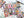Colorful puzzle with book-themed design on a white surface. Puzzle is mostly completed with a few puzzle pieces scattered nearby. Also visible is an open book, a poster of the puzzle design and the puzzle box lid.
