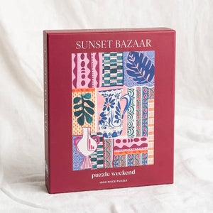 Puzzle box with colorful patterns titled 'Sunset Bazaar'. Red box has Puzzle Weekend branding on a white background