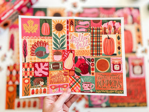 A hand holds an art print featuring a colorful autumn patchwork design with pumpkins, sunflowers, turkeys, leaves, and fall-themed illustrations. The background is a softly blurred mostly completed version of a puzzle featuring the same artwork.