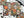 A Halloween-themed jigsaw puzzle with scattered pieces on a white surface, alongside the puzzle box, a black spiderweb material, and decorative spider and butterfly props. The puzzle design features sugar skull, jack-o'-lantern, candelabra, snakes, and autumn leaves on a dark background.