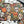 A Halloween-themed jigsaw puzzle with scattered pieces on a white surface, alongside the puzzle box, a black spiderweb material, and decorative spider and butterfly props. The puzzle design features sugar skull, jack-o'-lantern, candelabra, snakes, and autumn leaves on a dark background.
