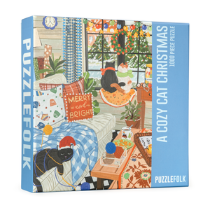 Puzzle box for 'A Cozy Cat Christmas' by PuzzleFolk, featuring a colorful illustration of a cozy living room with a black cat wearing a Santa hat and a blue plaid blanket.