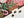 A close-up of a completed jigsaw puzzle showing a holiday floral design with red roses, green holly leaves, candy canes, and snowflakes on a dark brown background. Several loose puzzle pieces are scattered on a white surface.