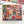 A puzzle box lid for a Halloween themed puzzle featuring artwork in a grid of different spooky images like skulls, pumpkins, witches, etc. Brand is Spaghetti Tree and it's 1000-pieces. Lid is next to a partial view of the completed puzzle, the edge of a few black sticks and a small portion of a print of the puzzle.