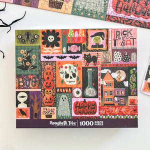 A puzzle box lid for a Halloween themed puzzle featuring artwork in a grid of different spooky images like skulls, pumpkins, witches, etc. Brand is Spaghetti Tree and it's 1000-pieces. Lid is next to a partial view of the completed puzzle, the edge of a few black sticks and a small portion of a print of the puzzle.