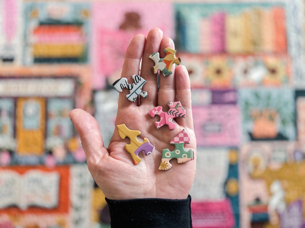 Hand holding colorful puzzle pieces with a blurred background of a puzzle