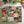 A 1000-piece jigsaw puzzle box by Spaghetti Tree featuring a colorful patchwork collage of Christmas motifs like Santa, snowflakes, wreaths, and 'JOY', 'NOEL', and 'MERRY' on a white background with pine branches at the top.