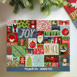 A 1000-piece jigsaw puzzle box by Spaghetti Tree featuring a colorful patchwork collage of Christmas motifs like Santa, snowflakes, wreaths, and 'JOY', 'NOEL', and 'MERRY' on a white background with pine branches at the top.