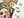A partially assembled jigsaw puzzle featuring a Day of the Dead theme with a green snake, orange flowers, and a yellow skull on a dark background, shown on a white surface with a few loose pieces beside it.
