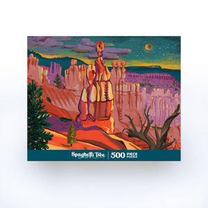 A 500-piece jigsaw puzzle box by Spaghetti Tree Puzzles, featuring a colorful illustration of a desert canyon landscape with a tall tree-like rock formation under a starry sky.