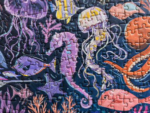 Jigsaw puzzle with ocean-themed design featuring jellyfish, fish, and coral.