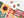 A colorful autumn-themed jigsaw puzzle partially assembled on a white surface, with several loose puzzle pieces scattered above it. The design features a large sunflower, pumpkins, leaves, and a pink scarf in warm orange, yellow, green, and pink tones.