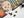 A partially assembled jigsaw puzzle featuring a colorful sugar skull and Halloween-themed illustrations on a dark background, with a few loose puzzle pieces on a white surface and a black spider decoration in the corner.