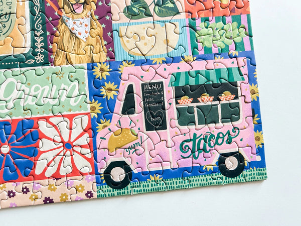 Close up of a colorful puzzle with taco truck, florals and food artwork on a white background