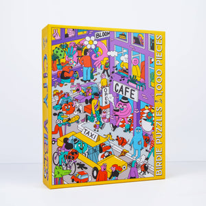 Photo of an angled jigsaw puzzle box against a white surface/wall. Box shows an illustration of a busy urban scene with many people and figures, including animal people going about their lives. 