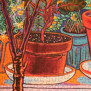 Colorful puzzle with potted plants and a hand holding a branch.