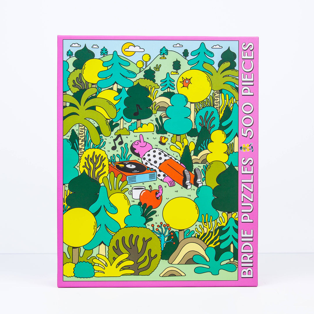 Jigsaw Puzzle box showing illustration of a man lying in the middle of a bunch of trees listening to music on a record player.