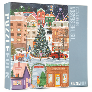 Puzzlefolk puzzle box with gray-blue brarnding and an image of a city with a large tree in the middle decked out for the holidays. 