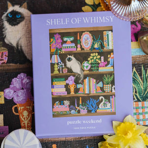 Shelf of Whimsy puzzle packaging with a cat on shelves illustration, surrounded by decorative items.