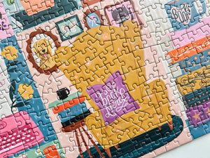 Jigsaw puzzle with a completed section showing a pillow on a chair with books and a cup.