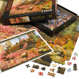 An open Art & Fable puzzle box atop a mostly completed version of the puzzle with pieces scattered on a white surface.  Also visible is a print of the same puzzle.