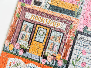 Partial view of a jigsaw puzzle showing an illustration of a bookshop with colorful design.